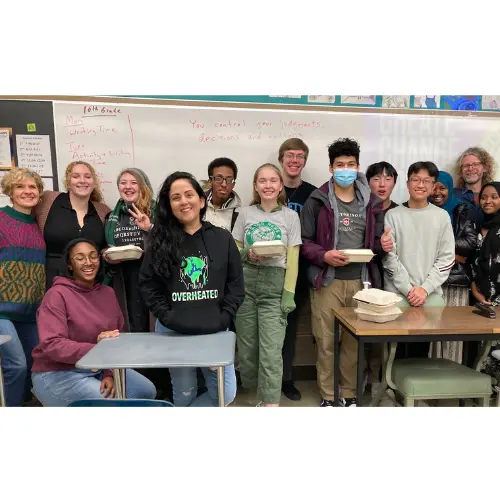 A group of students & program organizers in front of a whiteboard.